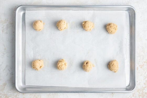 Cookie dough balls spread evenly across a baking sheet lined with parchment paper.