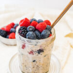 A jar of low calorie overnight oats topped with fresh mixed berries.