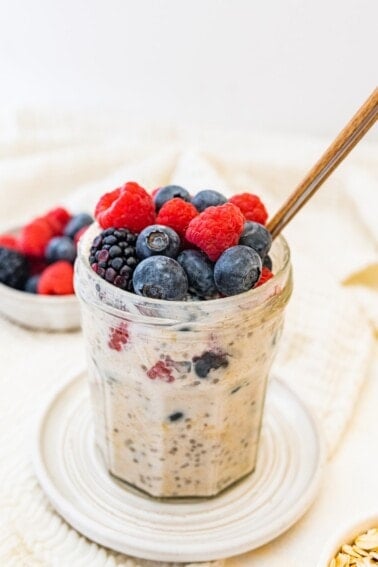 A jar of low calorie overnight oats topped with fresh mixed berries.