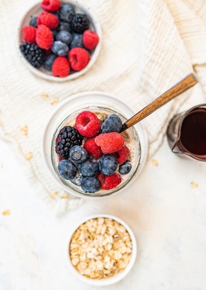 A jar of low calorie overnight oats topped with mixed berries.