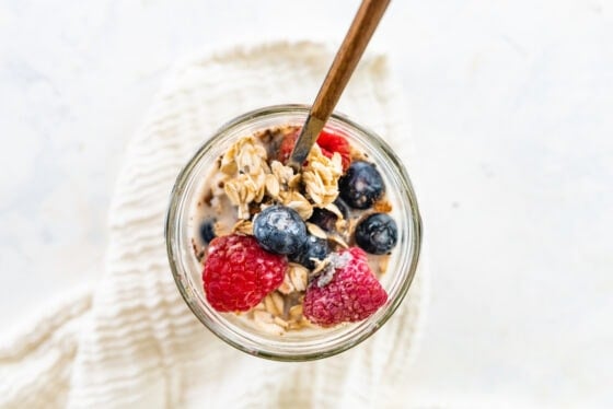 A spoon mixing together ingredients in a jar.