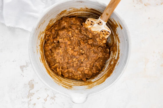 Oats and butterscotch chips mixed into mixture with spatula.