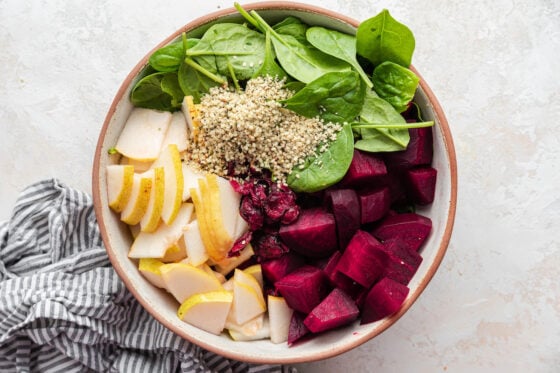 Pears, beets, spinach, hemp hearts and craisins in a bowl.