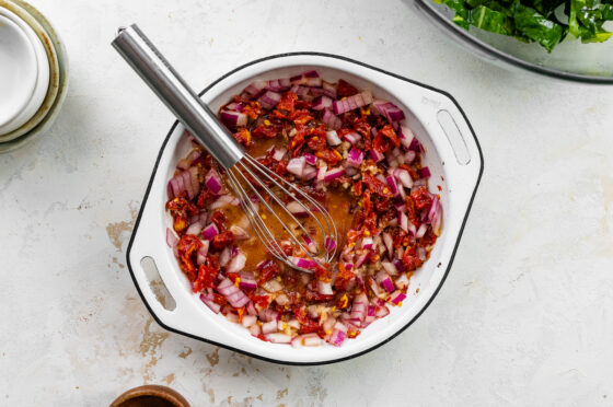 Dressing mixed together in a bowl with a whisk.