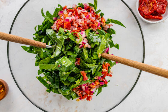 Dressing added to bowl with massaged collard greens.
