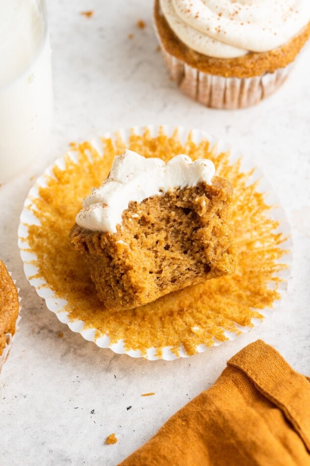An unwrapped sweet potato cupcake with a bite taken out of it.