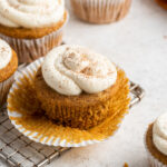 An unwrapped frosted sweet potato cupcake.