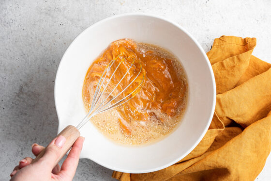 Whisking together wet ingredients in a bowl.