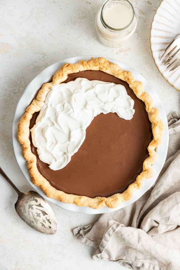 A vegan chocolate pie half covered with vegan whipped topping.