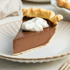 A slice of vegan chocolate pie with whipped topping on a plate.