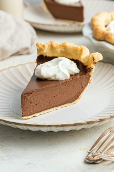 A slice of vegan chocolate pie with whipped topping on a plate.