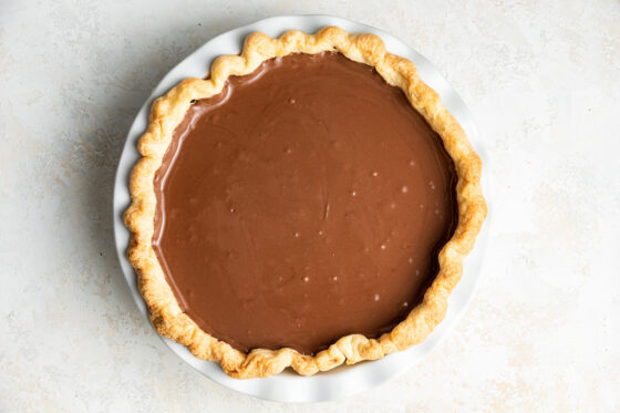 Chocolate pie filling added to a pie plate with pie crust.