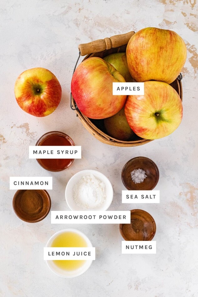 Ingredients measured out for the filling of Healthy Apple Crisp: apples, maple syrup, cinnamon, arrowroot powder, sea salt, lemon juice and nutmeg.