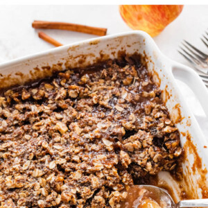Healthy apple crisp in a baking dish with a serving spoon.