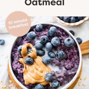 Bowl of blueberry oatmeal topped with blueberries, peanut butter and milk.