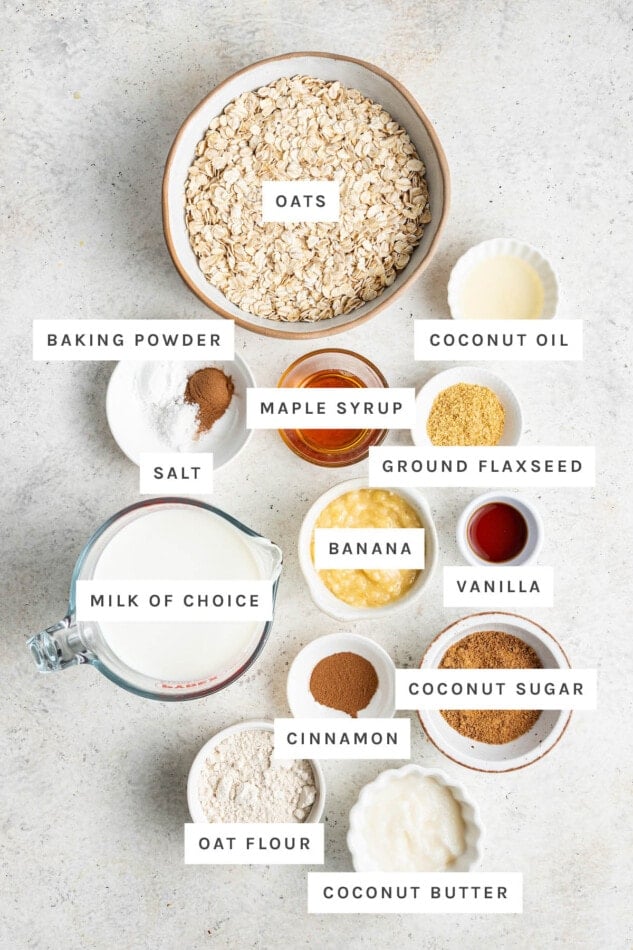 Ingredients measured out out to make Coffee Cake Baked Oatmeal: oats, baking powder, coconut oil, salt, maple syrup, ground flaxseed, banana, vanilla, milk, cinnamon, coconut sugar, oat flour and coconut butter.