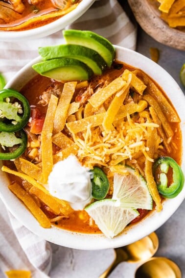 A bowl of chicken tortilla soup with toppings.