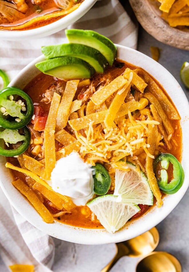 A bowl of chicken tortilla soup with toppings.