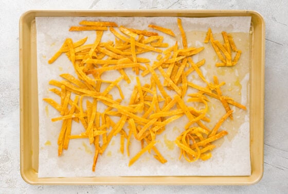 Baked tortilla strips on a sheet pan lined with parchment paper.