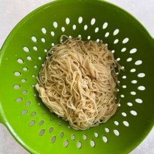 Cooked noodles in a strainer.