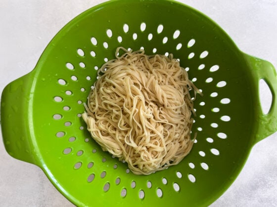 Cooked noodles in a strainer.