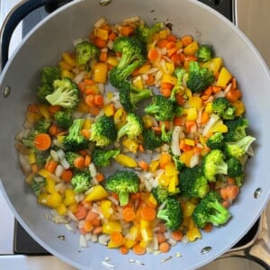 Vegetables cooking in a sauté pan.