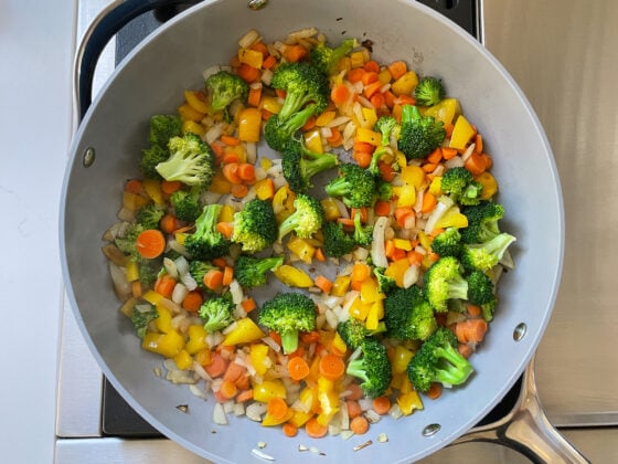 Vegetables cooking in a sauté pan.