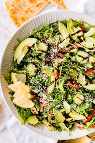 Bella Hadid's Salad in a serving bowl with lemon wedges.
