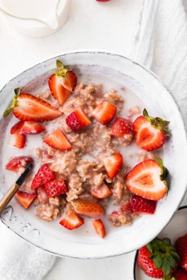 A bowl of oatmeal topped with strawberries.