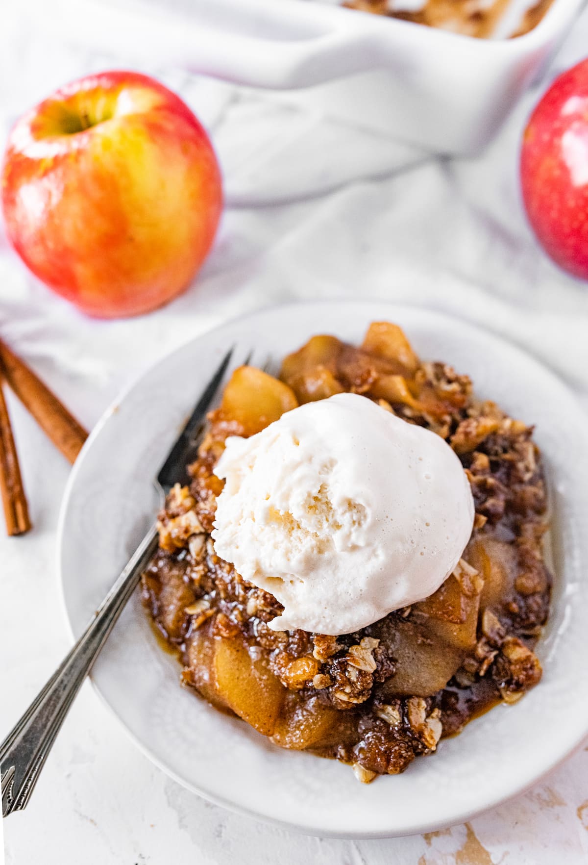A serving of apple crisp topped with ice cream.