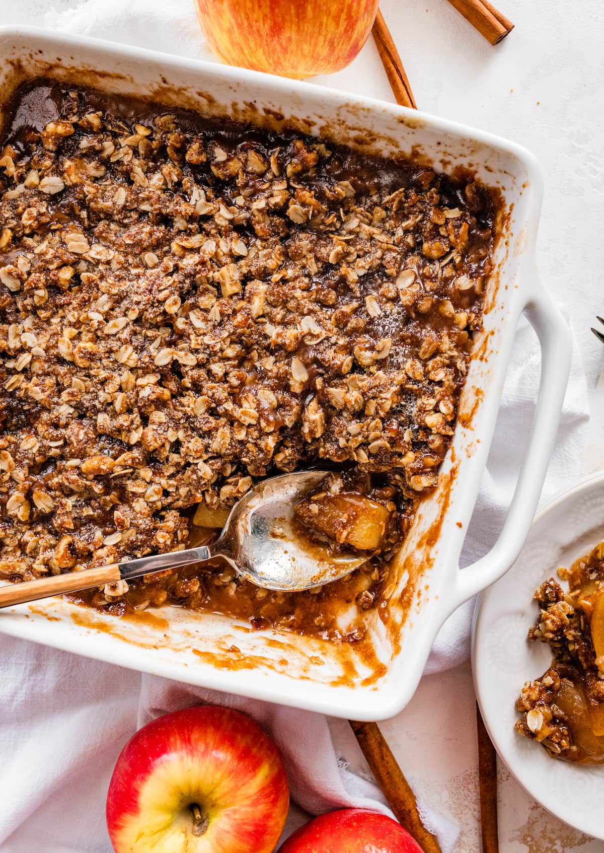 Healthy apple crisp in a baking dish with a serving spoon.