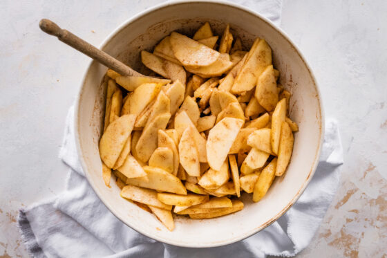 Apple slices in a bowl mixed with spices and sugar.