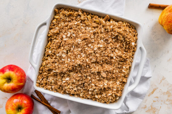Apple slices topped with oatmeal mixture in baking dish.