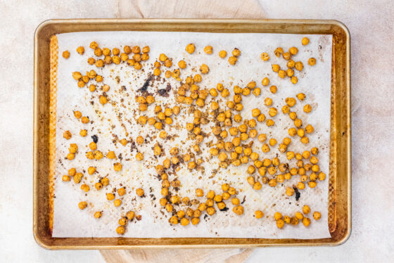 Roasted chickpeas on a parchment lined baking sheet.