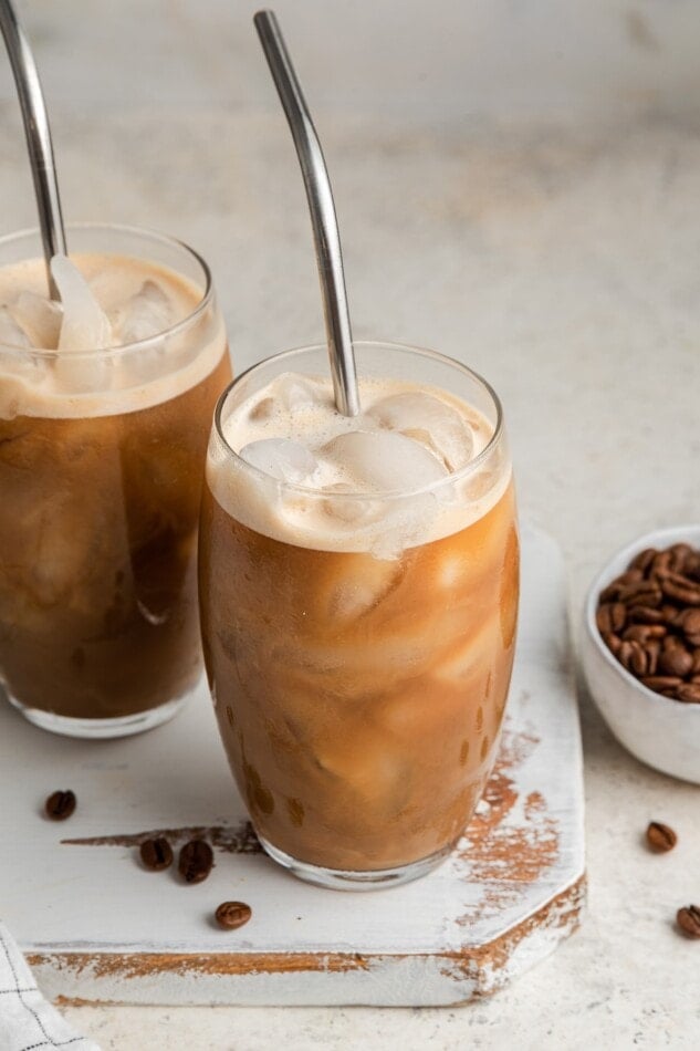 Two side by side glasses with straws containing protein coffee.