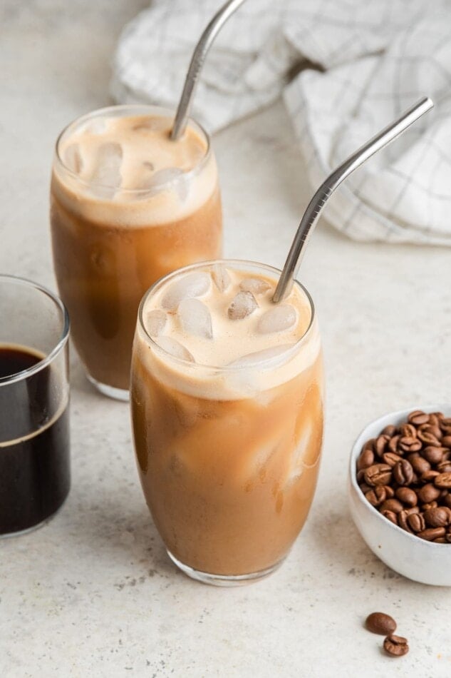 Two glasses with straws containing protein coffee.