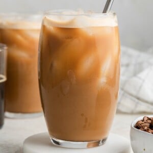 Protein coffee in a glass with ice and a straw.