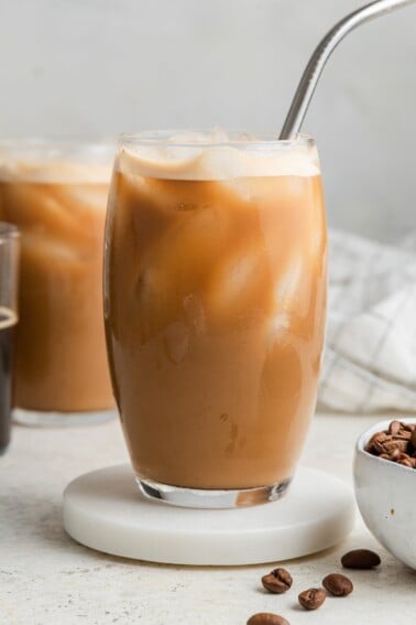 Protein coffee in a glass with ice and a straw.