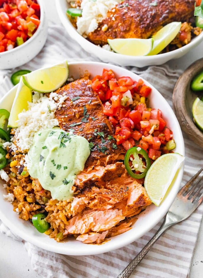 Salmon burrito bowl topped with avocado crema.