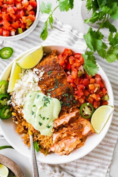 Salmon burrito bowl topped with avocado crema.