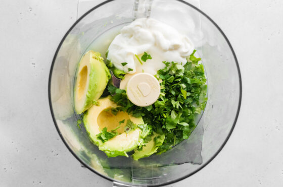 Ingredients for avocado crema in a food processor.