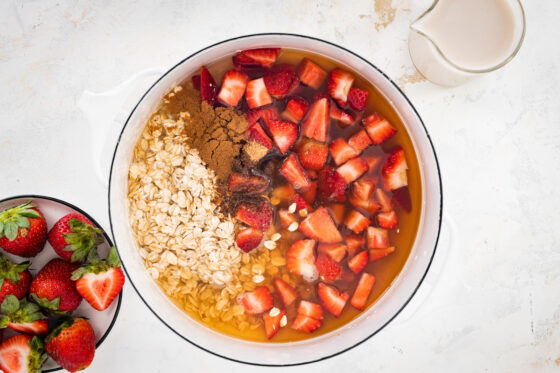 Ingredients for strawberries and cream oatmeal in a sauce pan.