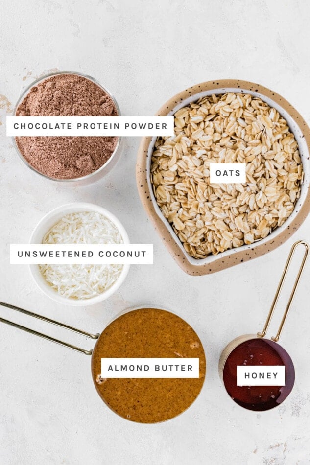 Ingredients measured out to make Almond Joy Protein Balls: chocolate protein powder, oats, unsweetened coconut, almond butter and honey.