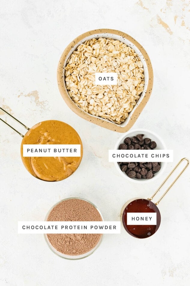 Ingredients measured out to make Chocolate Peanut Butter Protein Balls: oats, peanut butter, chocolate chips, chocolate protein powder and honey.