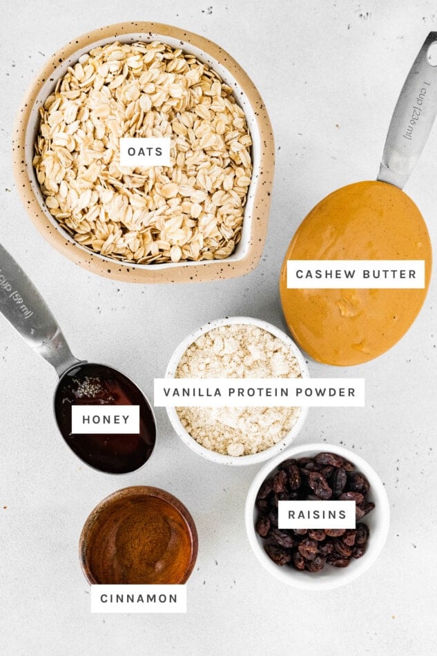 Ingredients measured out to make Cinnamon Raisin Protein Balls: oats, cashew butter, vanilla protein powder,honey, cinnamon and raisins.