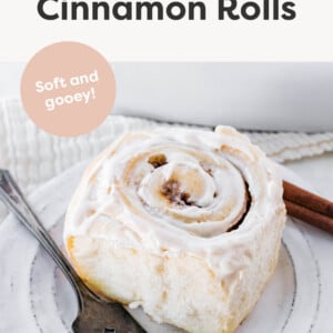 Fluffy homemade cinnamon roll on a plate with a fork.