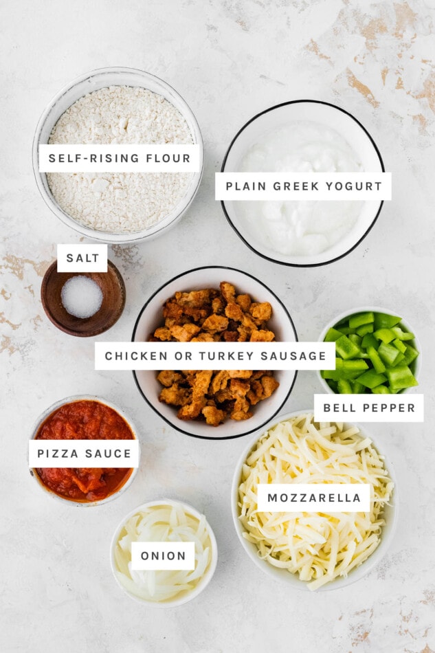 Ingredients measured out to make Protein Pizza: self-rising flour, plain Greek yogurt, salt, chicken/turkey sausage, bell pepper, pizza sauce, onion and mozzarella.