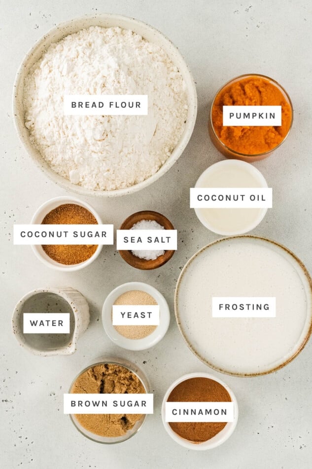 Ingredients measured out to make Vegan Pumpkin Cinnamon Rolls: bread flour, pumpkin, coconut oil, coconut sugar, sea salt, frosting, yeast, water, brown sugar and cinnamon.