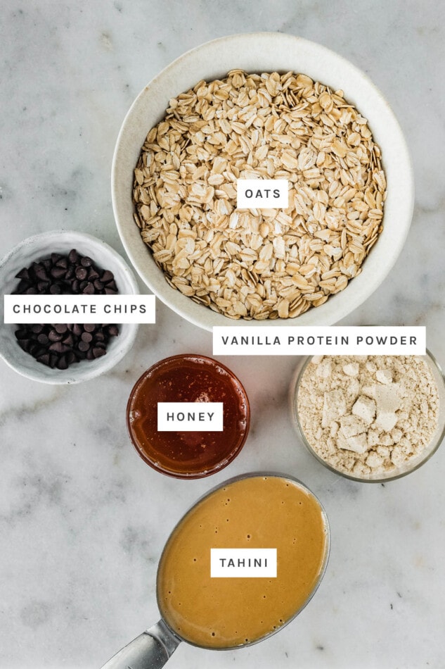 Ingredients measured out to make Tahini Chocolate Chip Protein Balls: honey, oats, chocolate chips, tahini and protein powder.