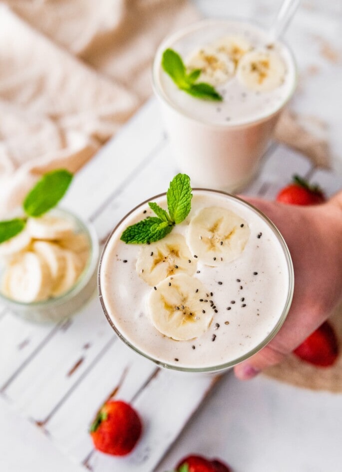 A hand holding up a banana protein shake.